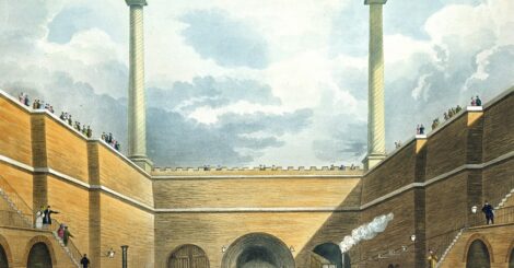 An image of the opening of the railway - it has an arch with two big chimneys and a rail track will people milling around the train.