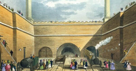 An image of the opening of the railway - it has an arch with two big chimneys and a rail track will people milling around the train.