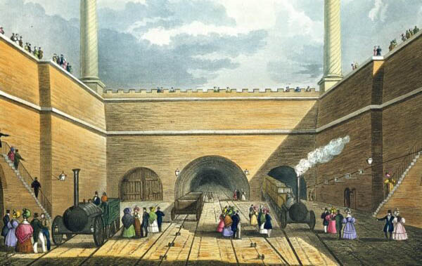An image of the opening of the railway - it has an arch with two big chimneys and a rail track will people milling around the train.