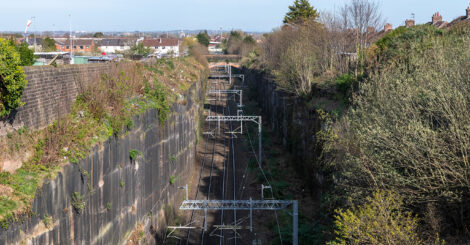 The railway disappears into the distance between towering sandstone walls, illustrating the remarkable scale of Olive Mount Cutting.