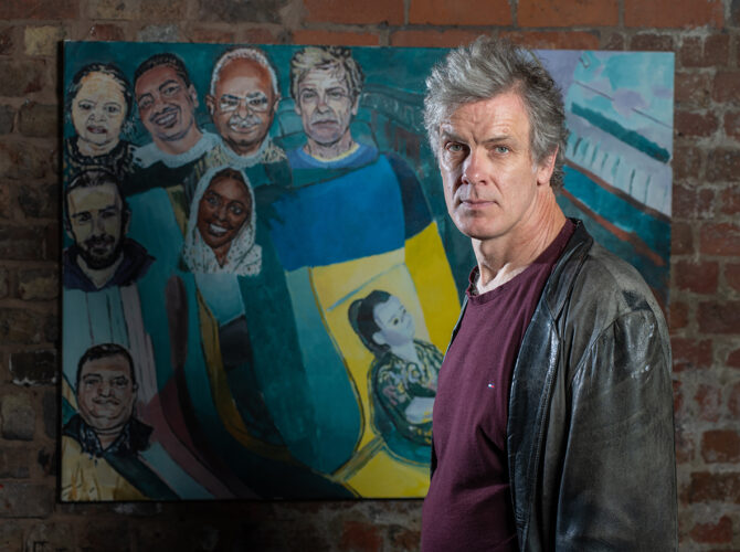 Mark Borgon standing in front of the colourful community artwork at Edge Hill Station.