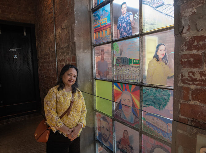 Friends Group member standing in front of the artwork installed in one of Edge Hill Station’s arched windows.