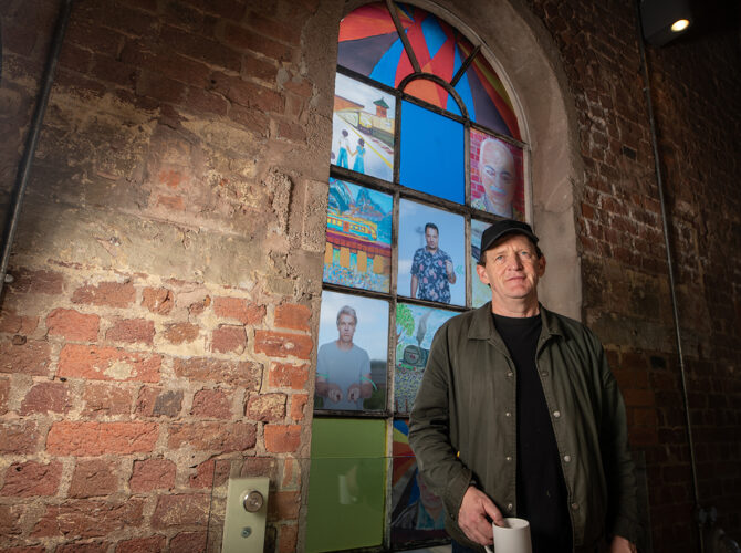 Friends Group member standing in front of the artwork installed in one of Edge Hill Station’s arched windows.